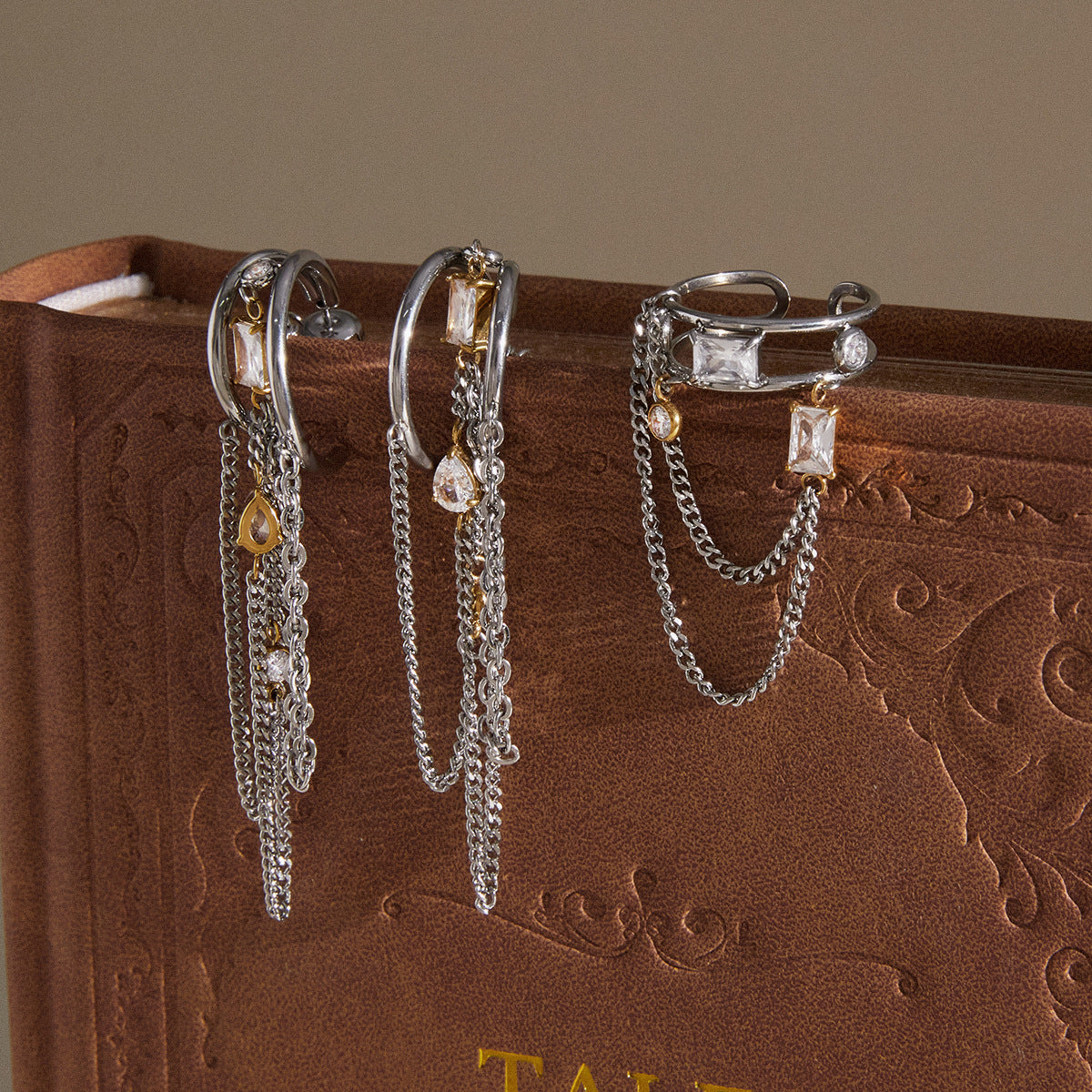 Two tone chain earrings and open ring displayed on a book