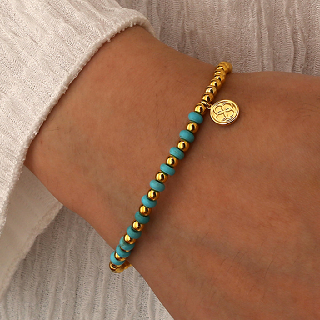 model wearing the slim gold and turquoise-color bead bracelet