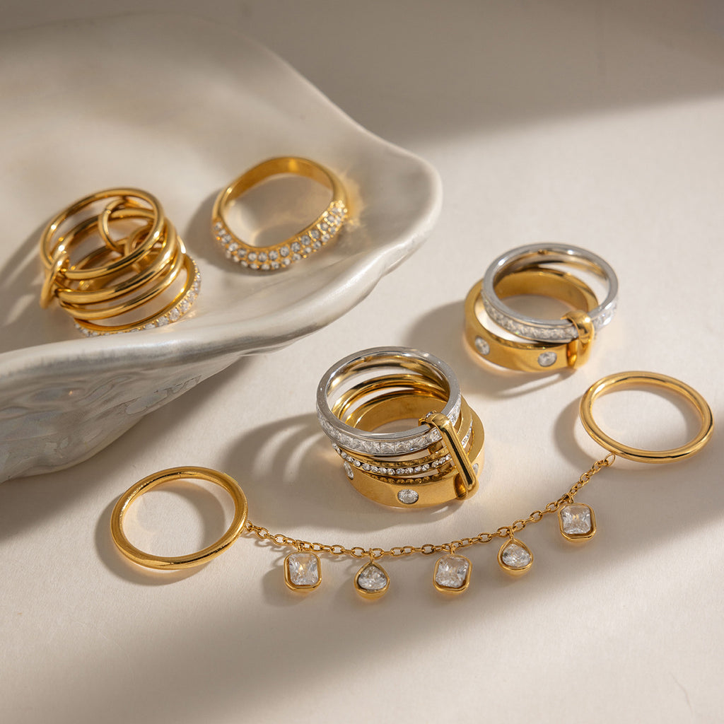 Gold-tone and mixed-tone rings beside a ceramic dish