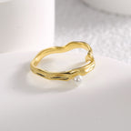 shell pearl set beside the raised leaf-like curves of the ring
