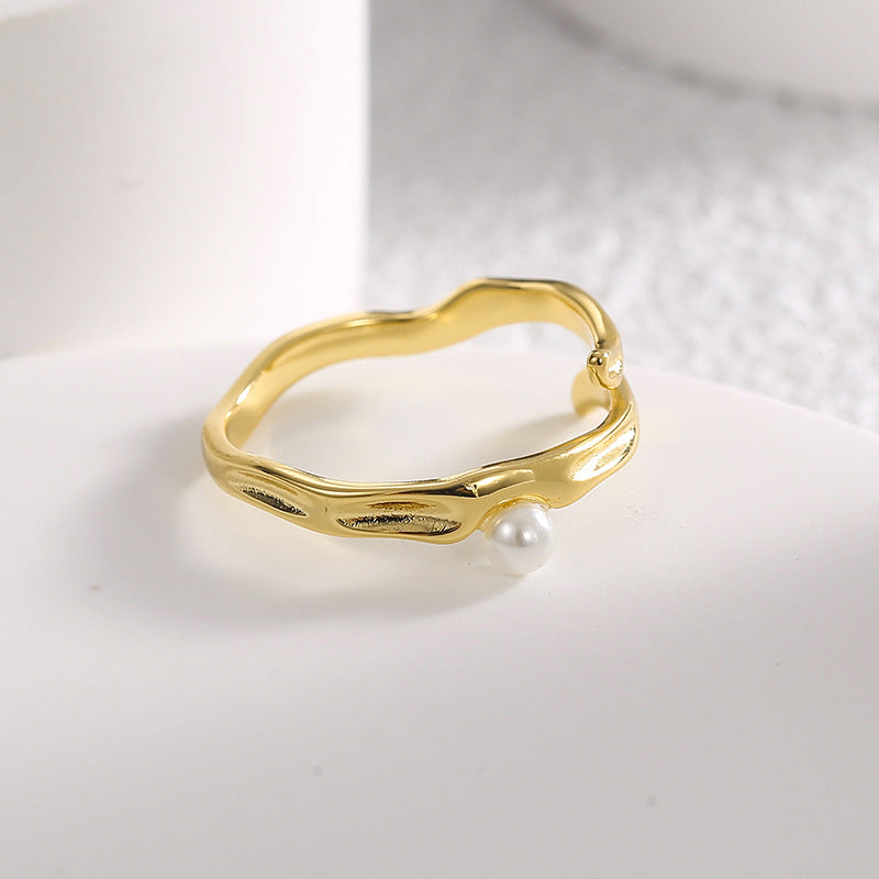 shell pearl set beside the raised leaf-like curves of the ring