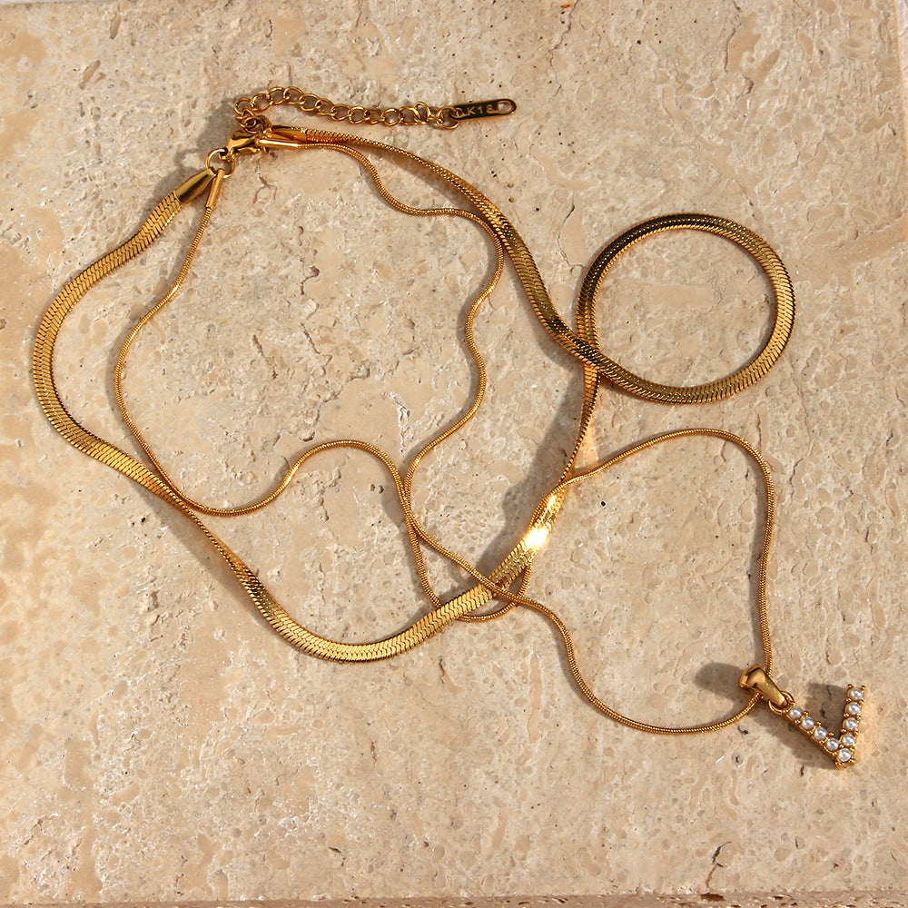 Layered imitation pearl initial necklace arranged on a stone surface