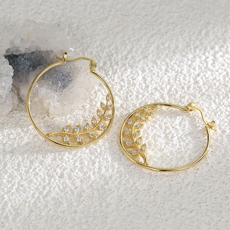gold plated leaf branch clear stone hoop earrings on pale stone