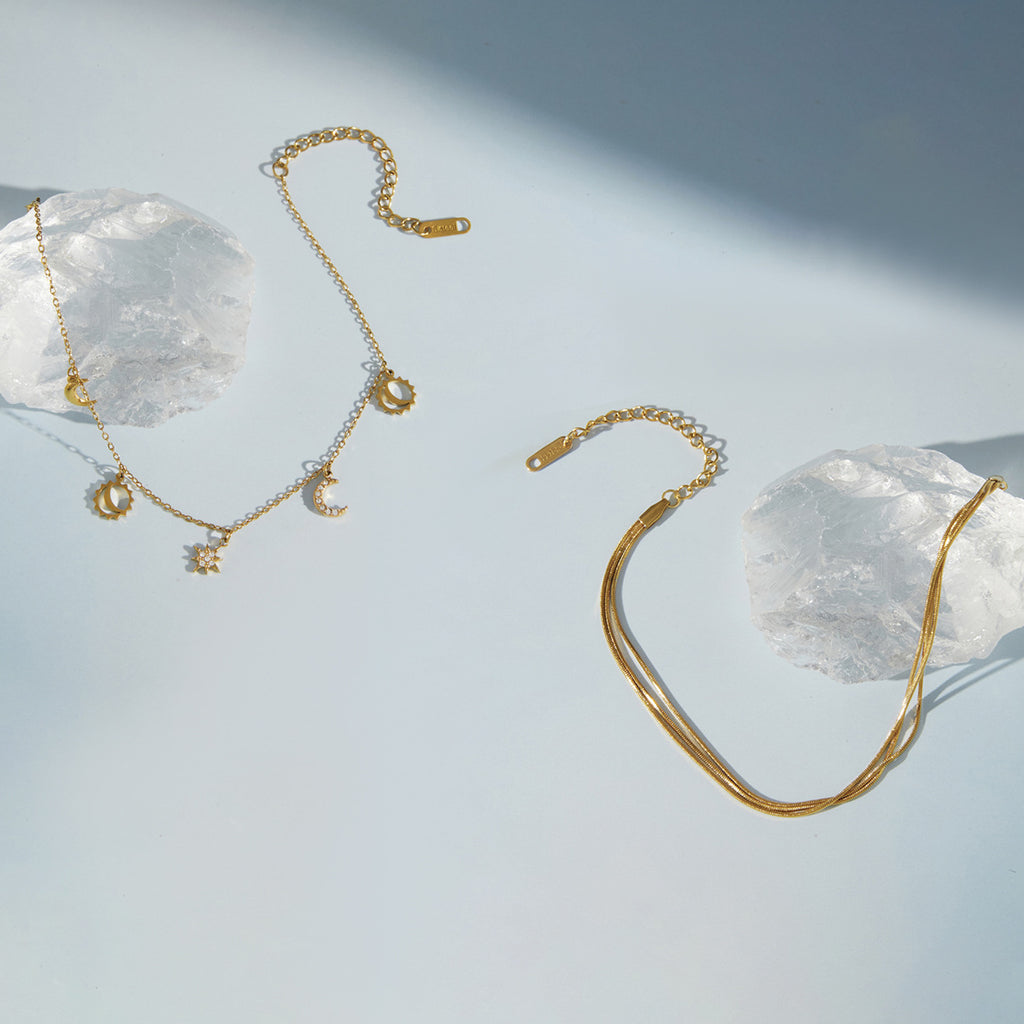 Two gold tone anklet designs displayed beside clear stones