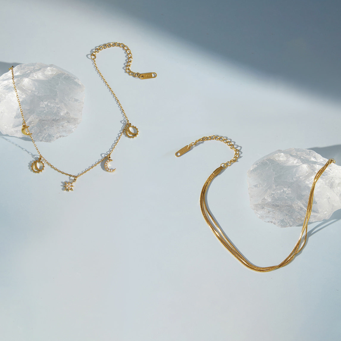 Two gold tone anklet designs displayed beside clear stones