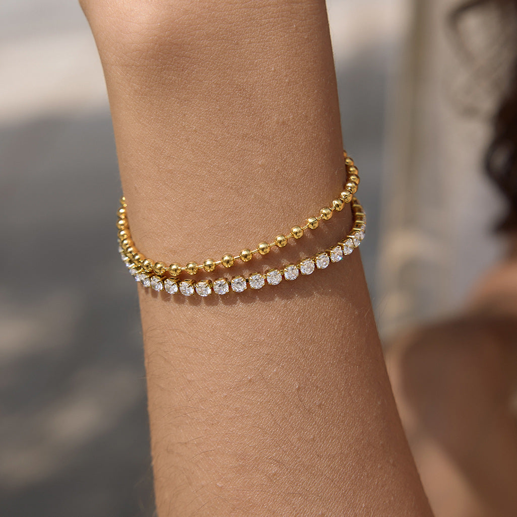 Gold-tone beads beside a clear stone row shown close-up