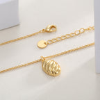 ribbed oval pendant necklace laid beside its lobster clasp and extender