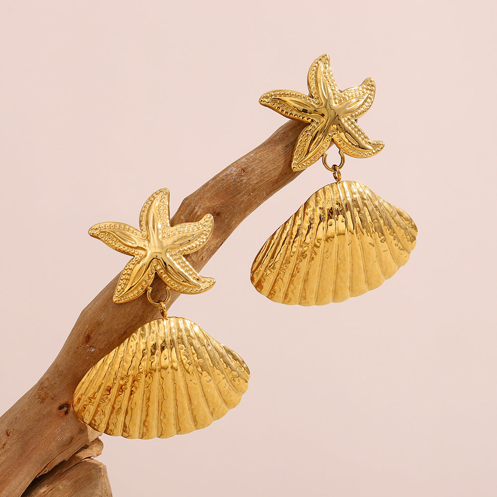 gold plated starfish and ridged shell drop earrings on wood
