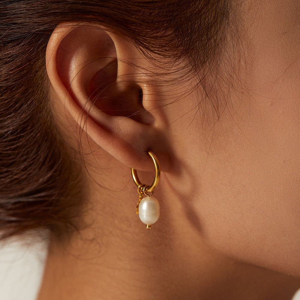 Close ear view of a gold plated hoop with an oval pearl drop