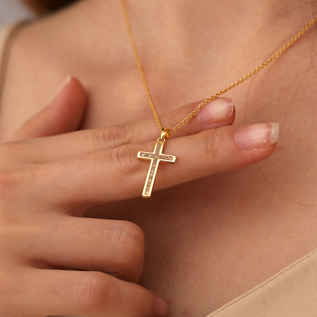 clear-stone cross pendant necklace worn at the collarbone
