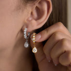 Silver tone teardrop huggie worn beside a gold tone version held in hand