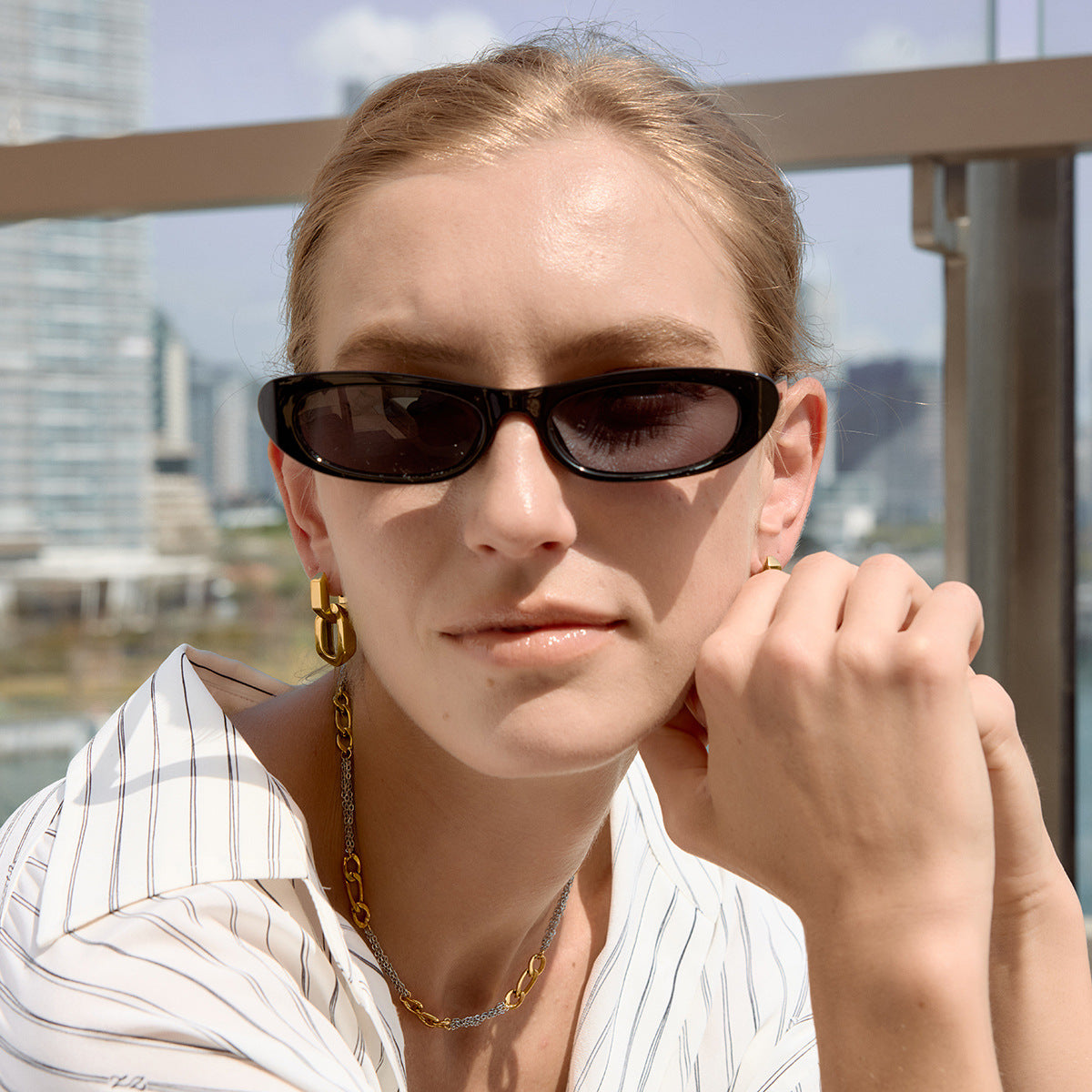 Gold tone oval link earrings worn with a striped shirt