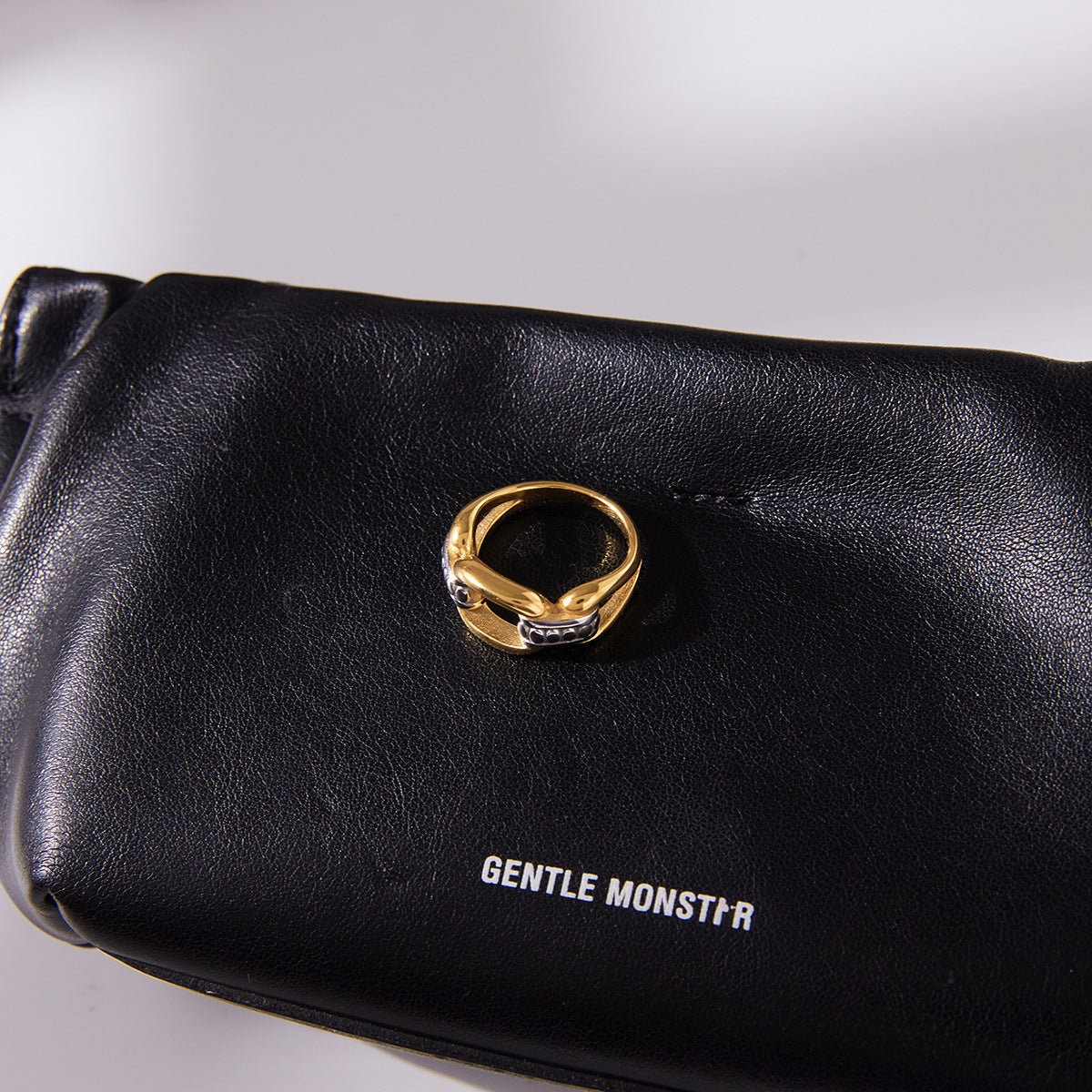 Gold- and silver-tone link ring displayed on a black pouch