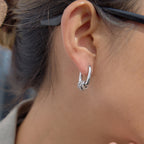 Silver-colored oval hoop with clear-stone ring charms shown worn