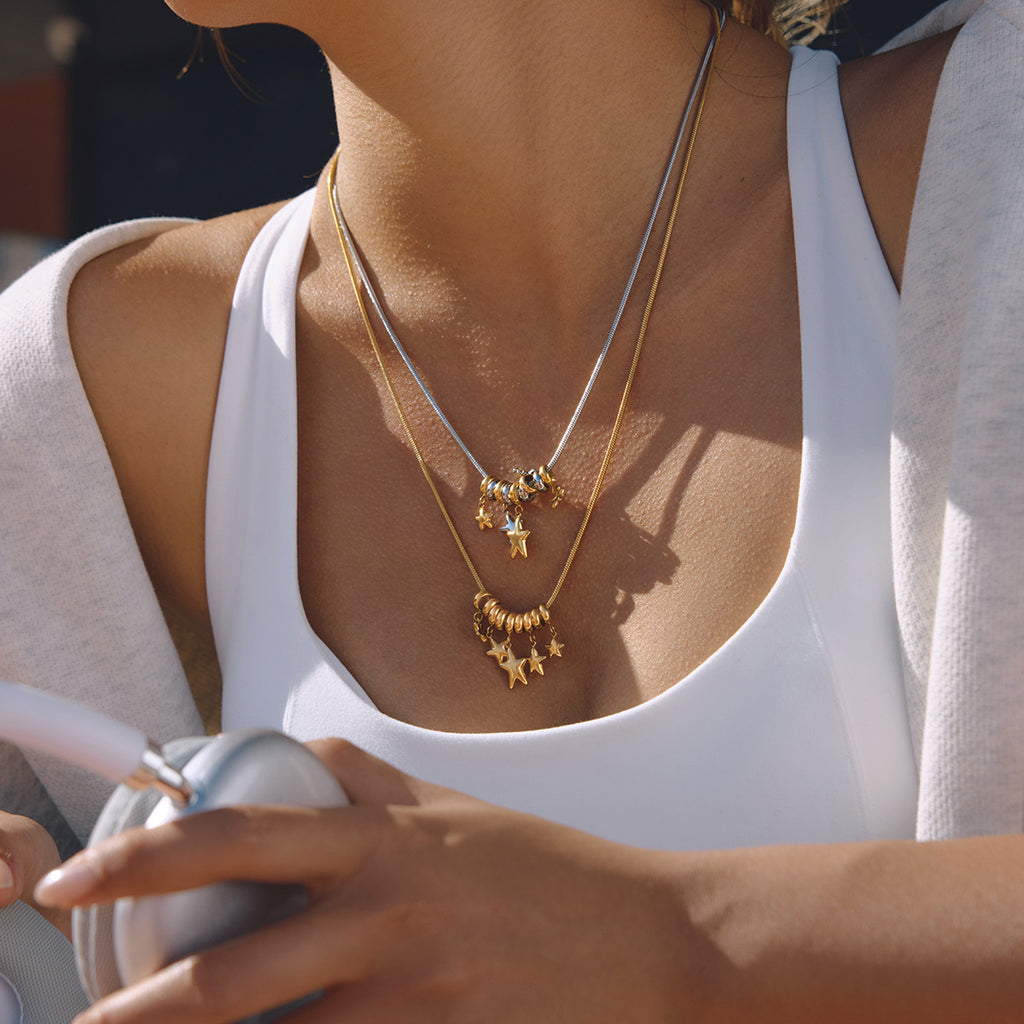 Gold and two-tone star cluster necklaces layered on a model
