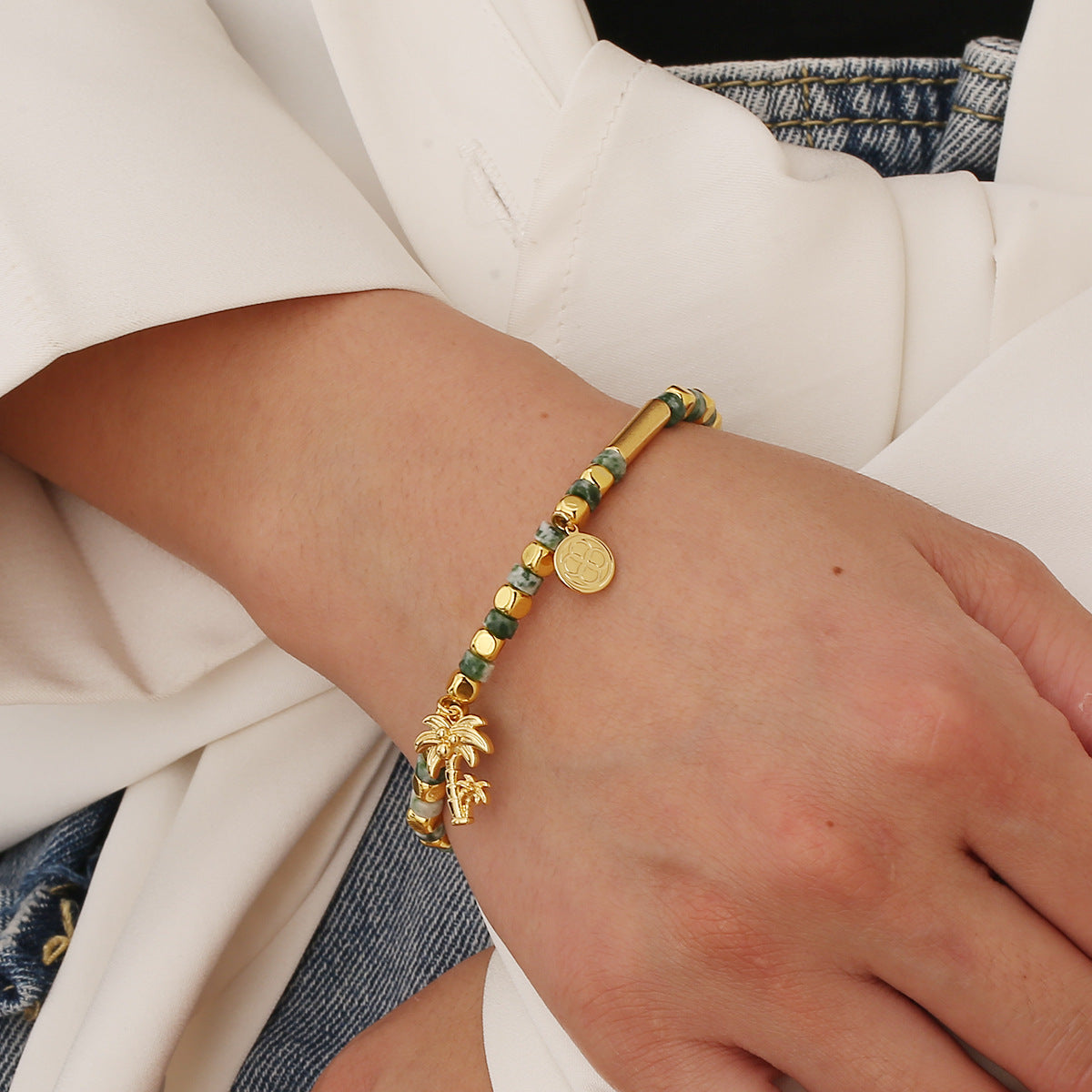 model wearing a green and gold plated palm tree bead bracelet