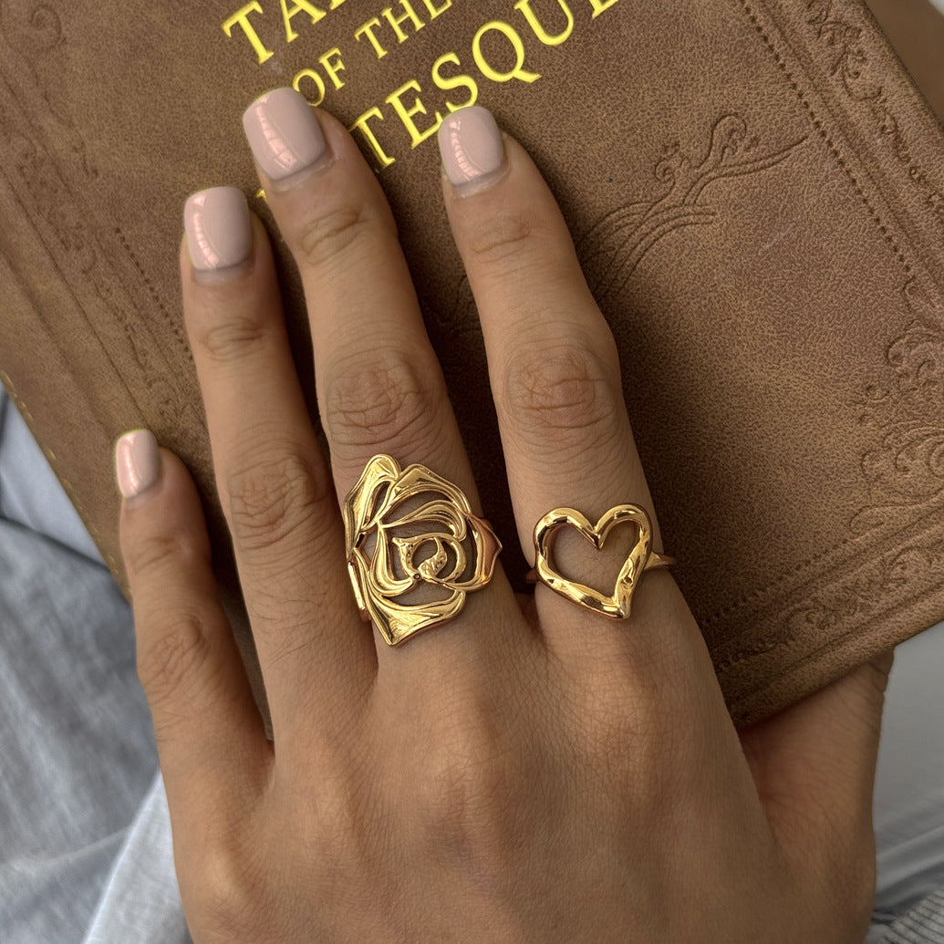 Gold tone rose ring beside an open heart on a hand