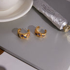 Multicolor stone-set hoops beside a cup