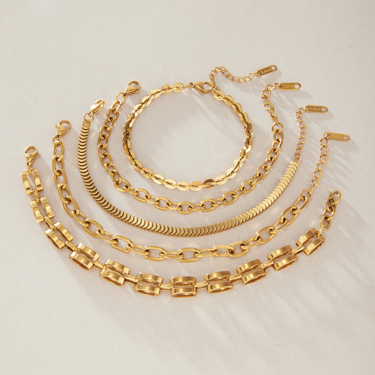 Flat oval twin-bar and overlapping-link bracelets laid out