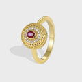 isolated gold plated red and clear stone medallion ring