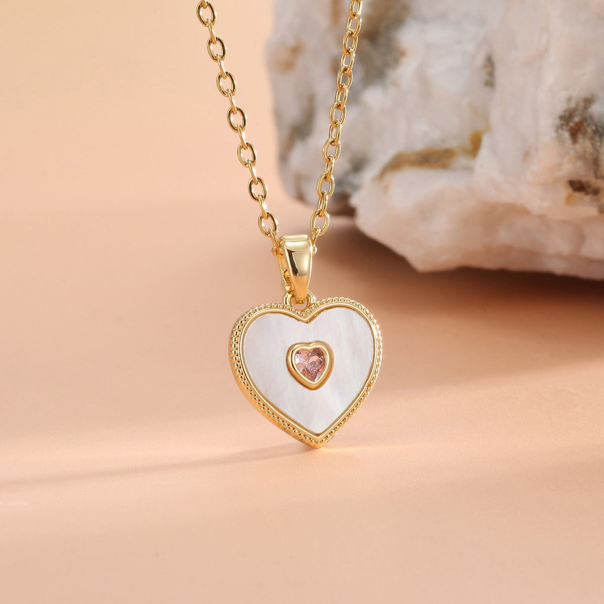 close view of the layered heart pendant beside a pale crystal