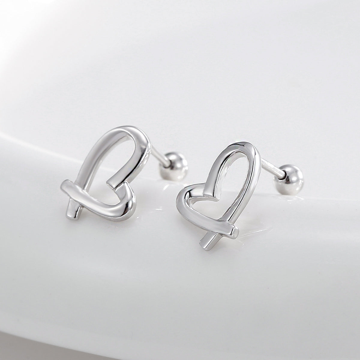 pair of open ribbon-heart ball-back earrings in an angled view