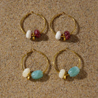 Burgundy and aqua resin bead hoops arranged on sand