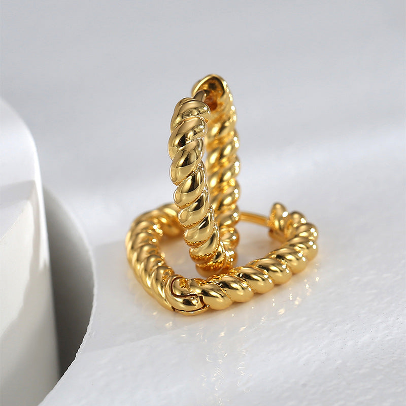 pair of gold plated twisted heart hoop earrings standing upright