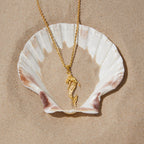 Stainless steel mermaid necklace displayed on a shell prop