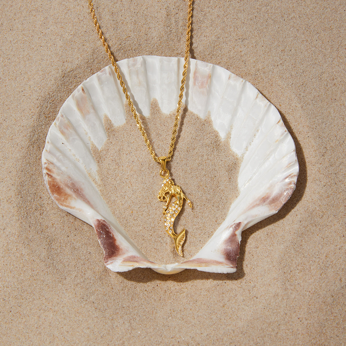 Stainless steel mermaid necklace displayed on a shell prop