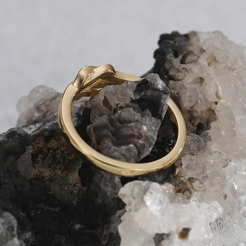 sculpted knot ring displayed across a dark mineral cluster
