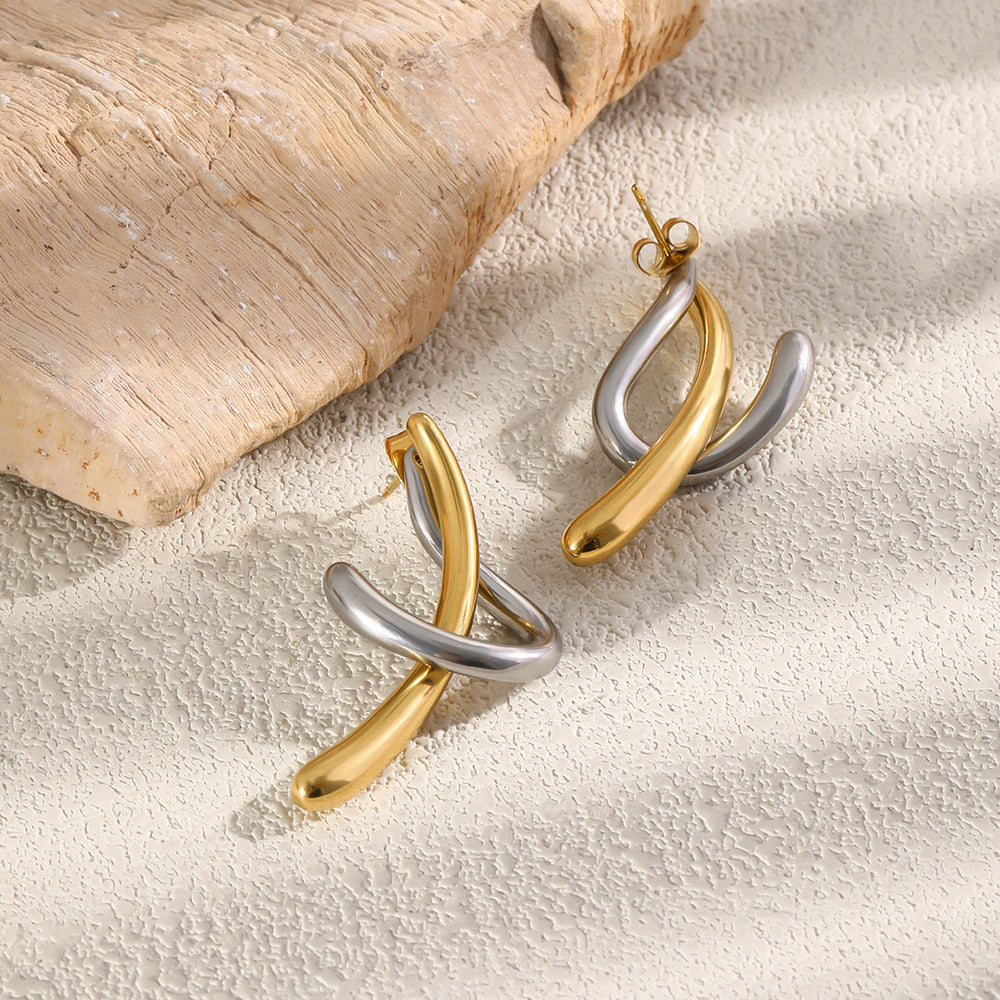 Polished curve earrings beside textured wood