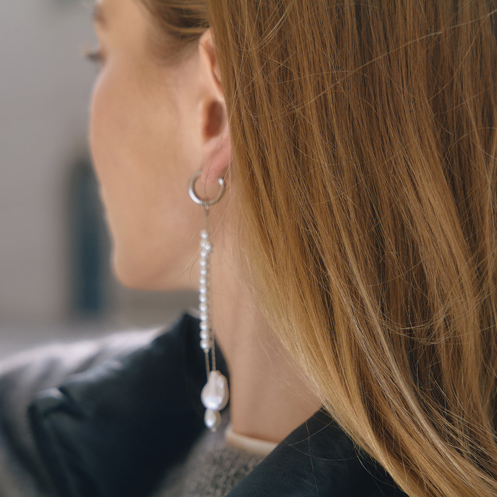 long mismatched white pearl-style bead earrings in side view