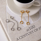 double-huggie chain earrings in two finishes beside a coffee cup