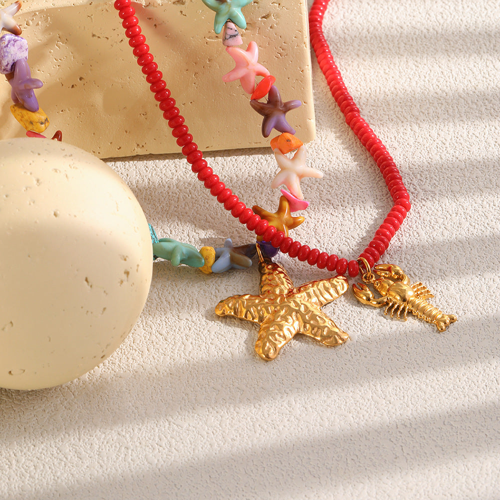 Starfish and lobster necklaces arranged beside pale stones