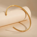 gold plated cuff bracelet showing its open ends and ribbed edge