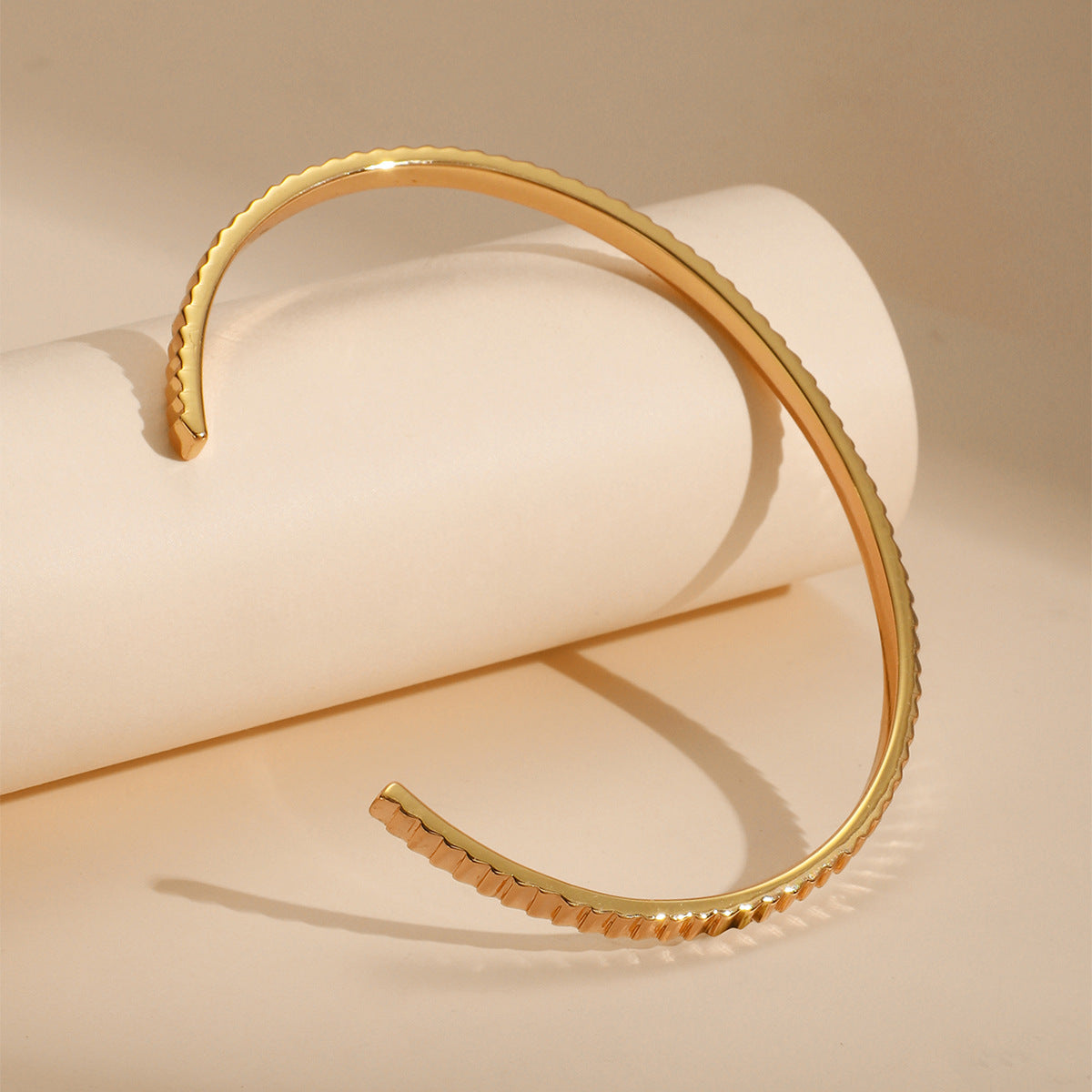 gold plated cuff bracelet showing its open ends and ribbed edge