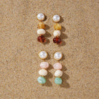 Warm and pastel three-bead earrings displayed on sand