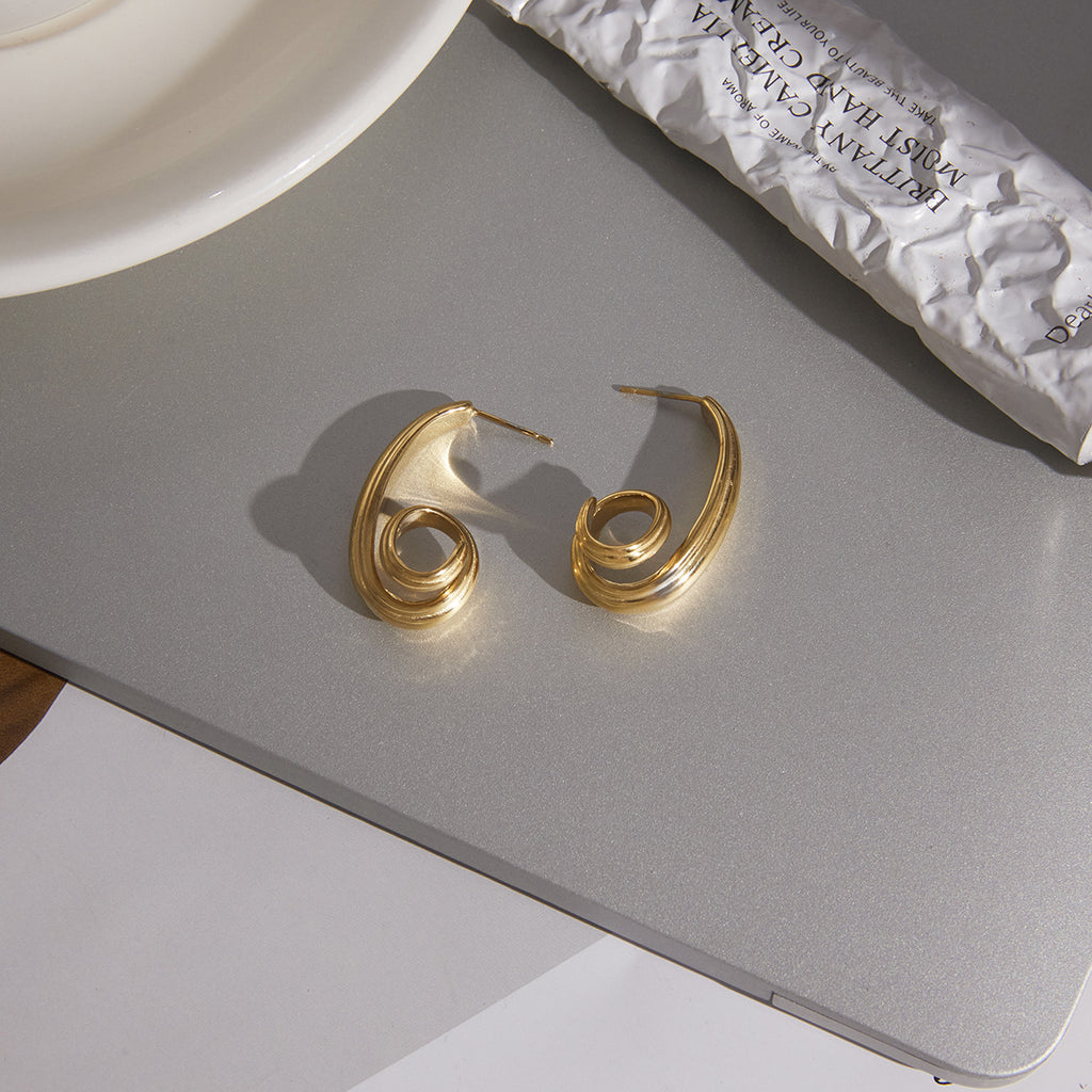 pair of gold plated triple-strand spiral earrings on a desk