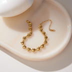 Gold tone heart bracelet arranged in a ceramic dish