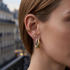 Two-tone open hoop earring worn on an ear