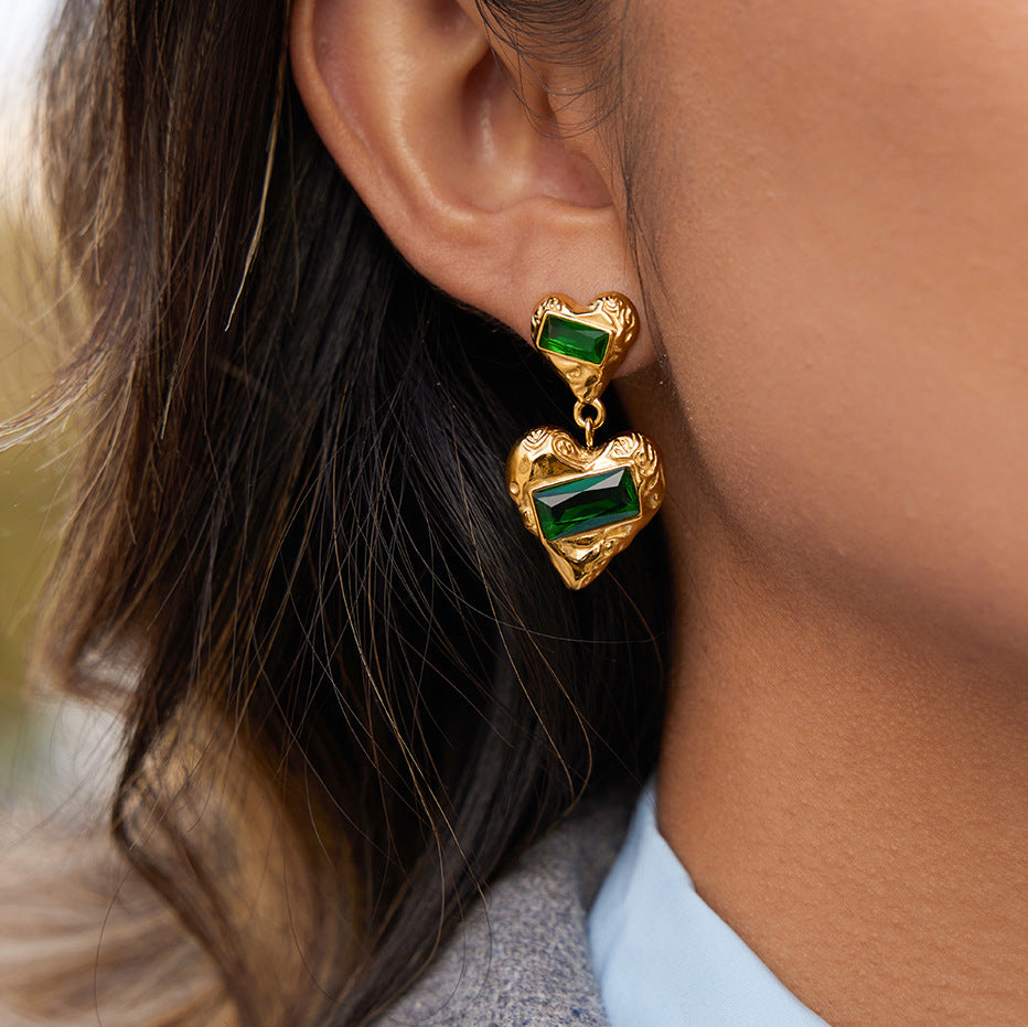 Green stone double-heart drop earrings worn beside the face