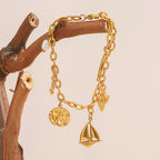 Gold Plated 316L Stainless Steel Coastal Charm Bracelet — hanging from wood with charms visible