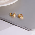 pair of oval clear-stone teardrop huggies on gray surface