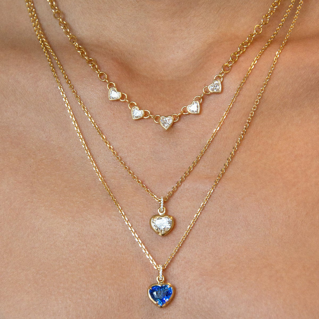 Five clear stone station necklaces layered on a model