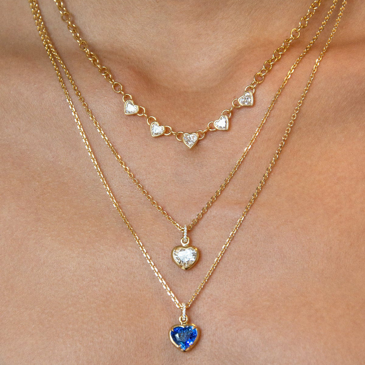 Five clear stone station necklaces layered on a model