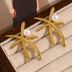 oversized gold plated palm pearl earrings displayed in a case