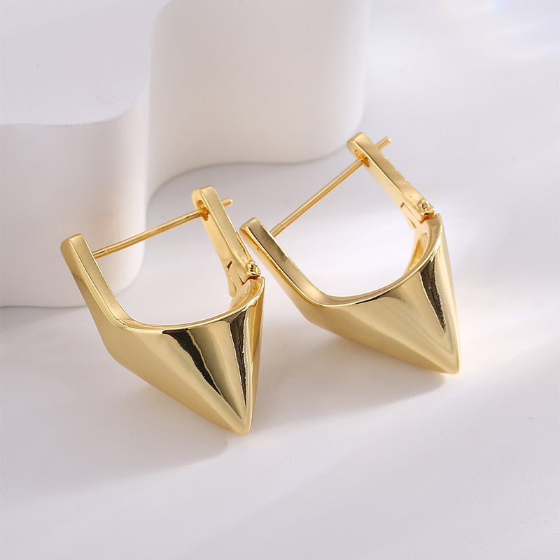 gold plated pyramid huggie hoop earrings in a front studio view