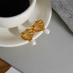 pair of botanical freshwater pearl earrings beside a coffee cup