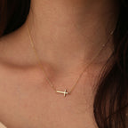 minimalist sideways cross necklace worn at the collarbone